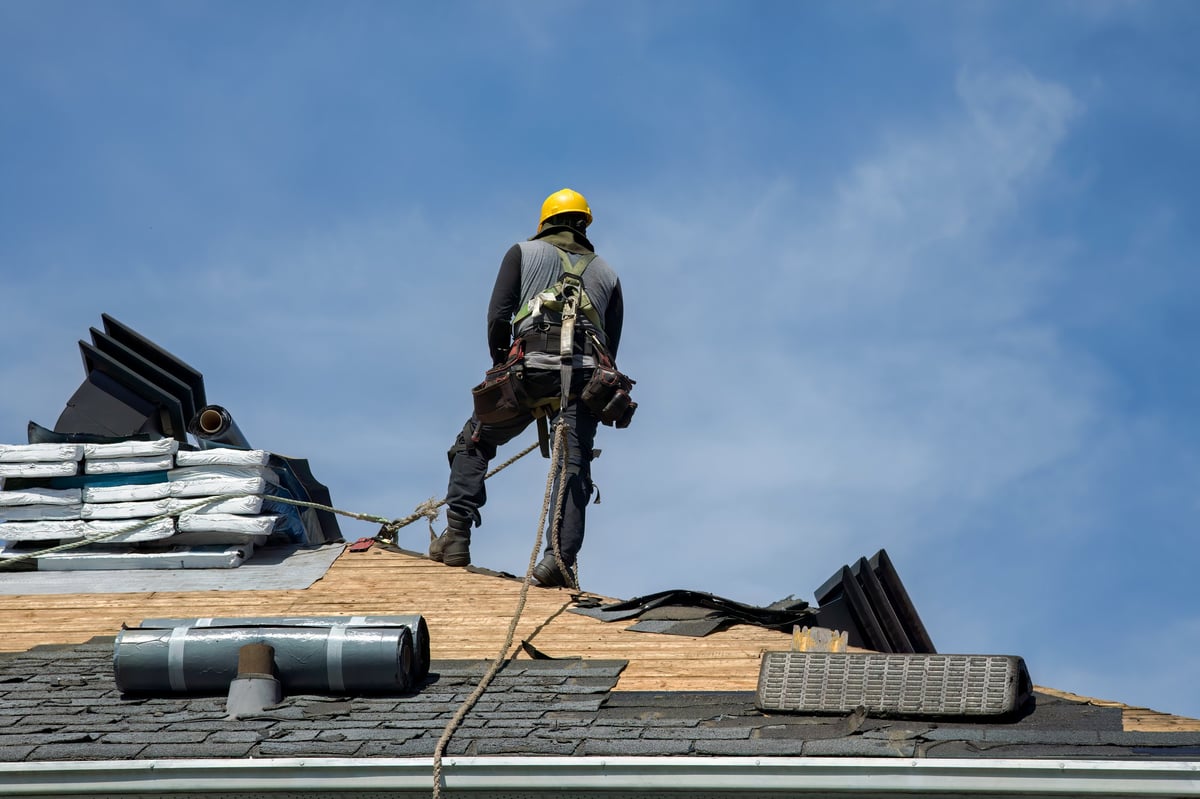 Construction worker with safety helmet applying roofing materials